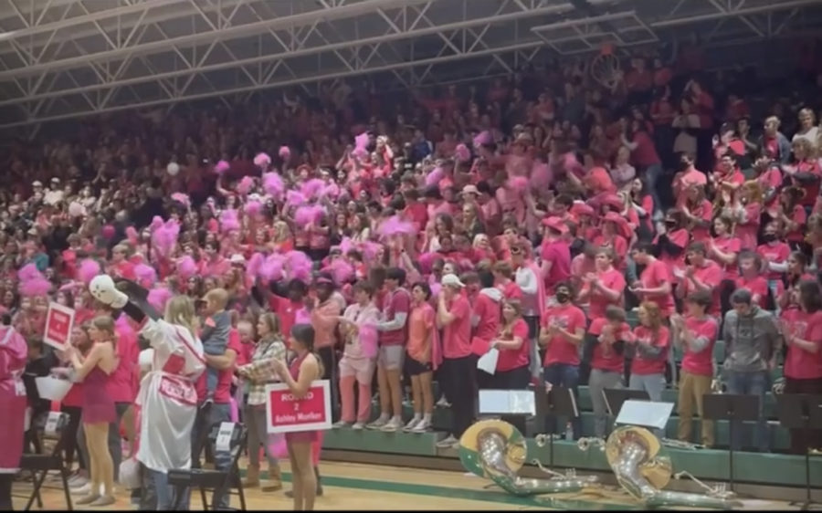 Jenisons cat pack studend section cheering on  their team during the basketball game. They are all dressed in pink to support the cause. 